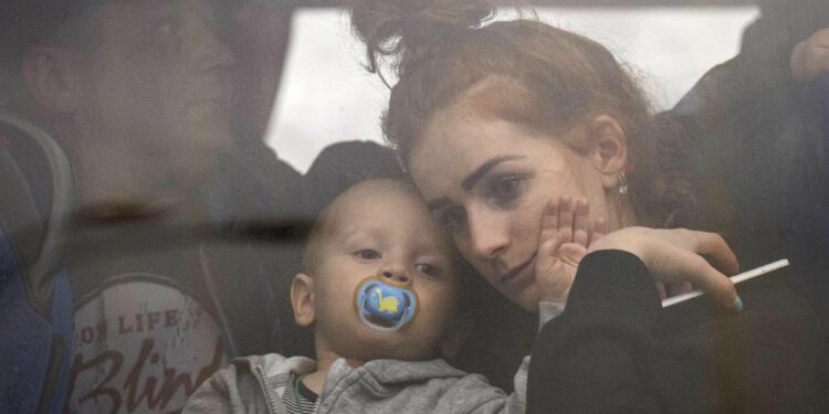 A woman holds her baby inside a bus as they leave Kyiv, Ukraine, Thursday, Feb. 24, 2022. EMILIO MORENATTI/THE ASSOCIATED PRESS