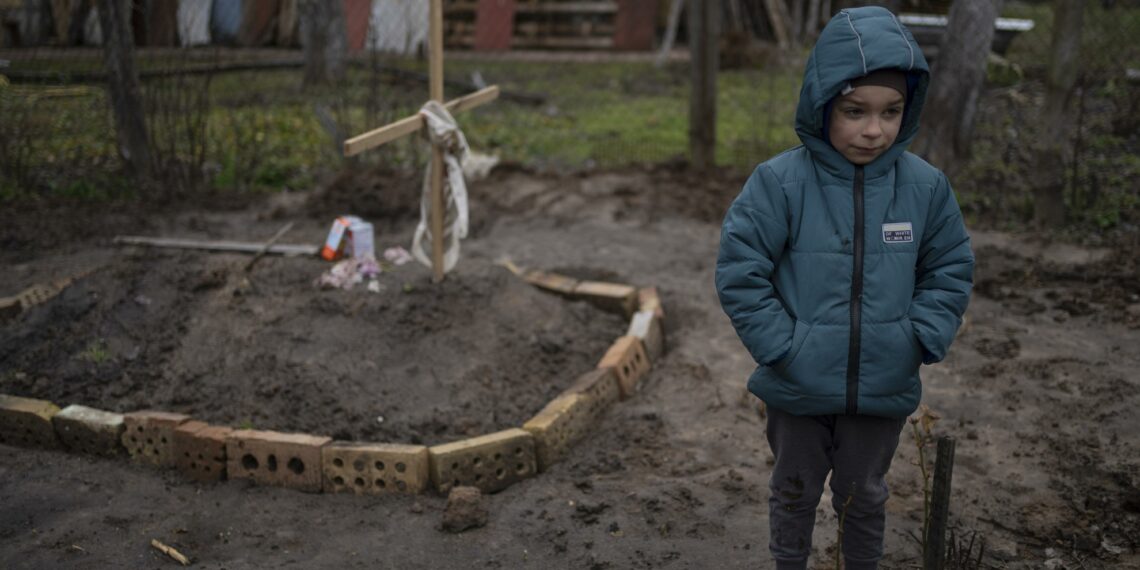 6-year-old boy on the grave of his mother, buried in the yard of their house. Bucha, on the outskirts of Kyiv, Ukraine, Monday, April 4, 2022. Russia is facing a fresh wave of condemnation after evidence emerged of what appeared to be deliberate killings of dozens if not hundreds of civilians in Ukraine. (AP Photo/Rodrigo Abd)