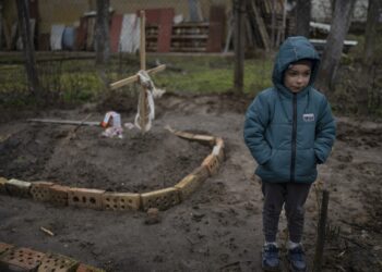 6-year-old boy on the grave of his mother, buried in the yard of their house. Bucha, on the outskirts of Kyiv, Ukraine, Monday, April 4, 2022. Russia is facing a fresh wave of condemnation after evidence emerged of what appeared to be deliberate killings of dozens if not hundreds of civilians in Ukraine. (AP Photo/Rodrigo Abd)