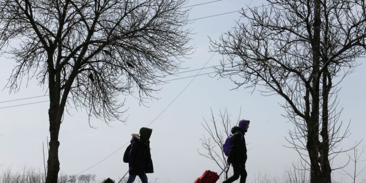 Refugees walk along a road as they leave the city during Ukraine-Russia conflict in the besieged southern port of Mariupol, Ukraine March 20, 2022. REUTERS/Alexander Ermochenko