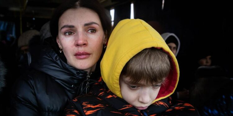 © IMF A mother and her son wait to be evacuated from the besieged city of Mikolayiv in Ukraine in March 2022.
