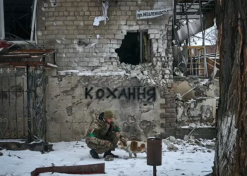 Ukrainian military man with a dog. The inscription on the wall translates as "Love". Photo by Libkos / AP / Scanpix / LETA