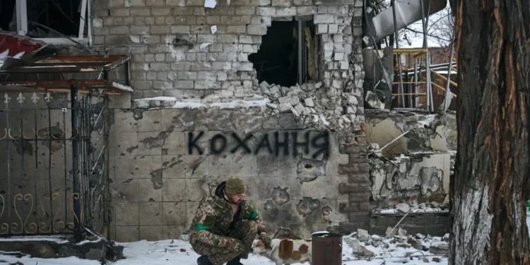 Ukrainian military man with a dog. The inscription on the wall translates as "Love". Photo by Libkos / AP / Scanpix / LETA