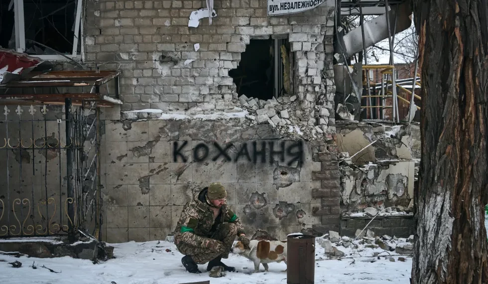 Ukrainian military man with a dog. The inscription on the wall translates as "Love". Photo by Libkos / AP / Scanpix / LETA