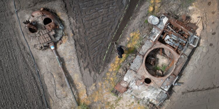 A peasant plants sunflower in his garden between the damaged Russian tank and its turret in the village of Velyka Dymerka, Kyiv region, Ukraine, Wednesday, May 17, 2023. (AP Photo/Efrem Lukatsky)