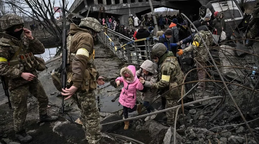 People cross a destroyed bridge as they evacuate the city of Irpin, northwest of Kyiv, during heavy shelling and bombing, 10 days after Russia launched a full-scale invasion of Ukraine, on March 5, 2022. (Aris Messinis/AFP via Getty Images)
