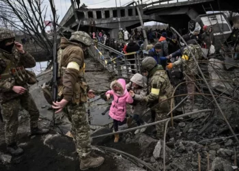 People cross a destroyed bridge as they evacuate the city of Irpin, northwest of Kyiv, during heavy shelling and bombing, 10 days after Russia launched a full-scale invasion of Ukraine, on March 5, 2022. (Aris Messinis/AFP via Getty Images)