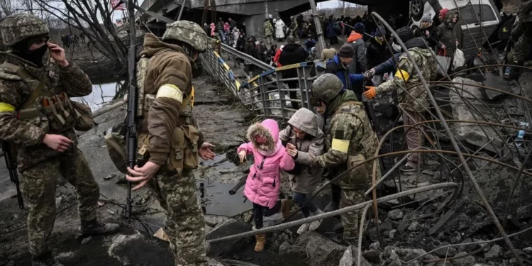 People cross a destroyed bridge as they evacuate the city of Irpin, northwest of Kyiv, during heavy shelling and bombing, 10 days after Russia launched a full-scale invasion of Ukraine, on March 5, 2022. (Aris Messinis/AFP via Getty Images)