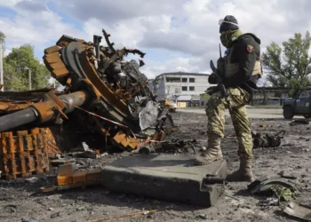 A Ukrainian soldier stands near pieces of a Russian tank Tuesday in the Kharkiv region. (Andrii Marienko / Associated Press)