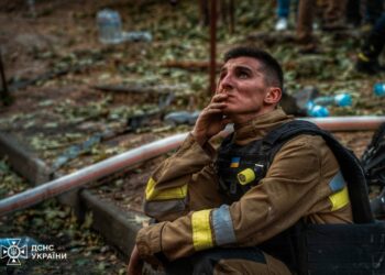 A Russian air strike on a house. This is an ordinary multi-storey residential building in Kharkiv. A tired rescuer is watching his colleagues extinguish a fire in this building. Photo by the State Emergency Service of Ukraine
