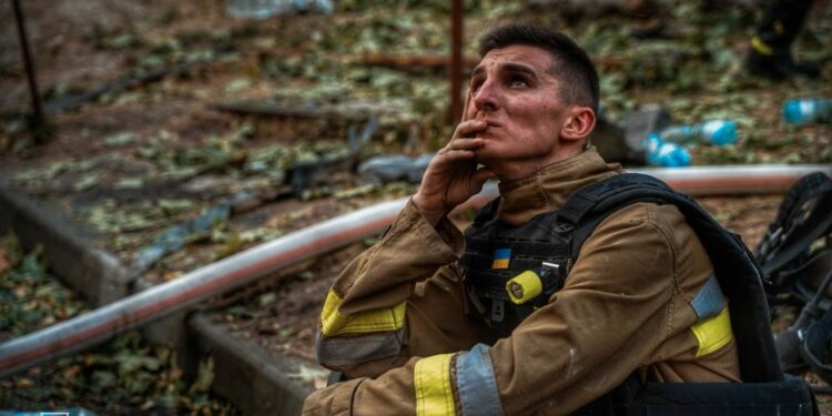 A Russian air strike on a house. This is an ordinary multi-storey residential building in Kharkiv. A tired rescuer is watching his colleagues extinguish a fire in this building. Photo by the State Emergency Service of Ukraine