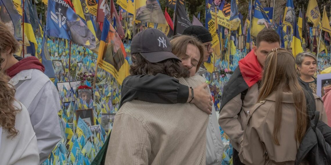 Two people embrace at a memorial for Ukrainian and foreign fighters on Defenders Day in Kyiv, Ukraine, on Oct. 1, 2024. (Roman Pilipey / AFP via Getty Images)