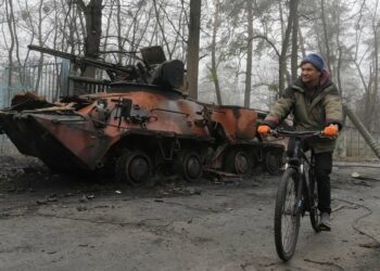 A man rides a bicycle past destroyed military equipment in Irpin near Kyiv, Ukraine, April 1, 2022: Efrem Lukatsky / AP