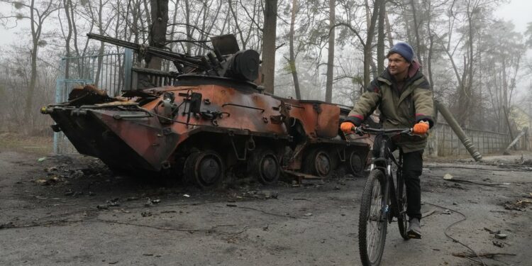 A man rides a bicycle past destroyed military equipment in Irpin near Kyiv, Ukraine, April 1, 2022: Efrem Lukatsky / AP