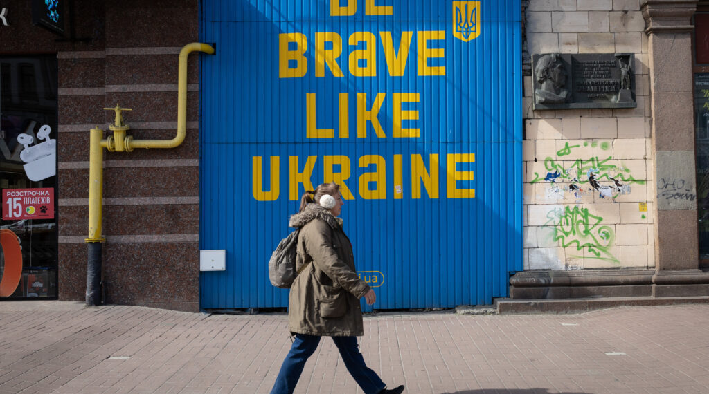 A woman walks near a building with a huge inscription 'Be brave like Ukraine' in central Kyiv.