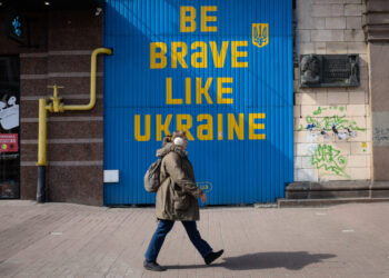 A woman walks near a building with a huge inscription 'Be brave like Ukraine' in central Kyiv.