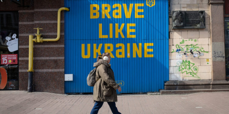 A woman walks near a building with a huge inscription 'Be brave like Ukraine' in central Kyiv.